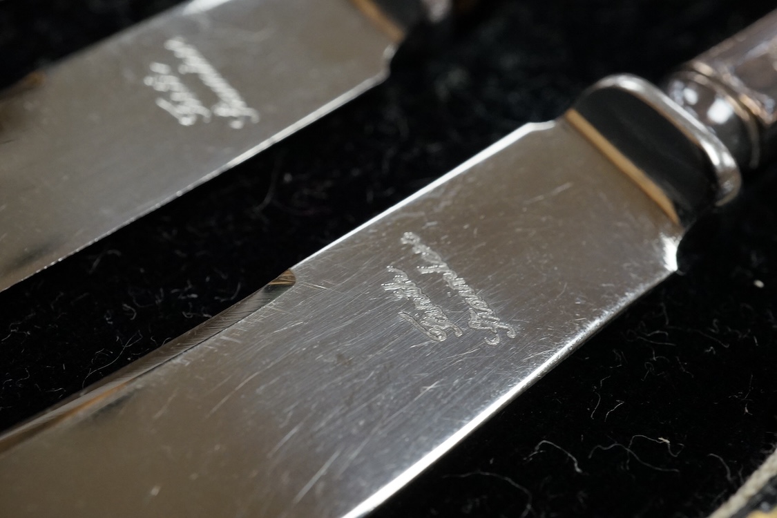 A cased set of twelve Edwardian silver apostle teaspoons with a pair of sugar tongs, Cooper Brothers & Sons, Sheffield, together with a cased Victorian silver bread knife and a cased set of six silver handled steel tea k
